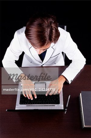 young businessman on the computer on a black background. Studio shot