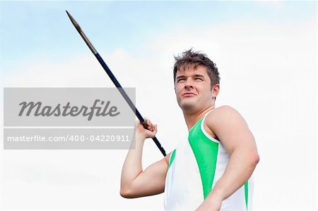 Handsome male throwing a javelin outdoors in a stadium