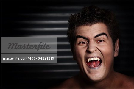 A portrait of a young agressive vampire over dark background