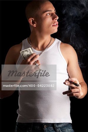 A good looking, muscular built, man on a black background smoking cigar.