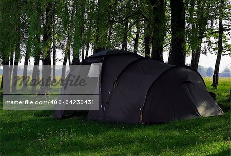 Green camping tent on green grassbackground