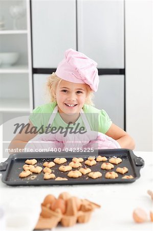 Adorable little girl showing her cookies to the camera standing in the kicthen