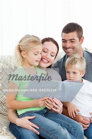 Adorable family reading a book together in the living-room at home