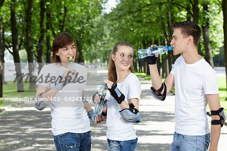 Young people in equipment in park drink water