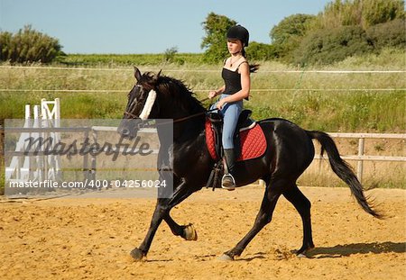 young girl and her black stallion in a training of dressage