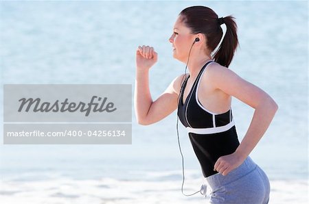Young woman running on the beach listening music