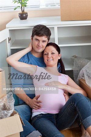 happy couple in their new home sitting on the floor among cardboard boxes in their new kitchen