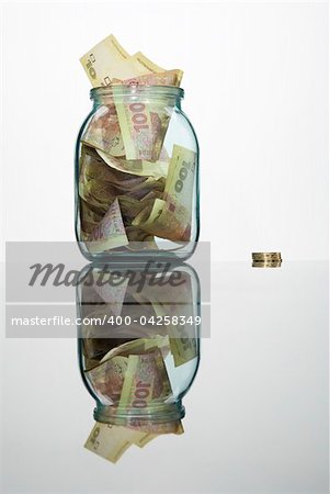 Glass jar full of hundreds of grivnas isolated on white background