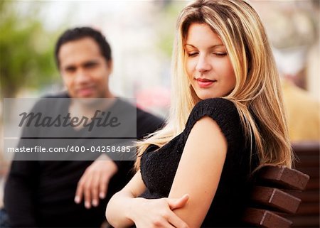 A man and woman sitting on a bench, the woman looking sky