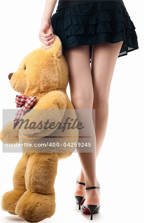 woman wearing skirt and high heels, holding toy bear near her legs, view of the back lower body part, isolated on white background