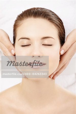 Portrait of charming well-groomed girl, in process massage of the face isolated