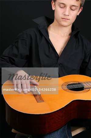 Teenage male in casual attire holding a guitar. FOCUS ON GUITAR by HAND
