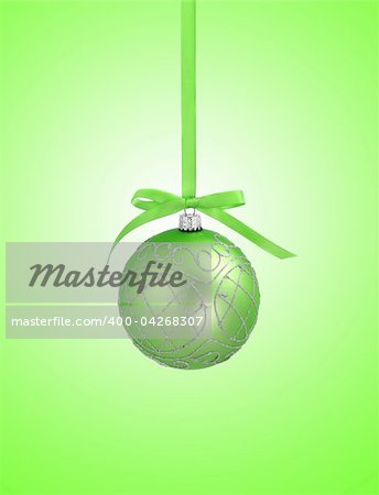 Green christmas ball with ribbon on green background with copy space for text