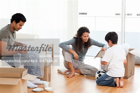 Happy family packing dishes together in their living-room for their removal