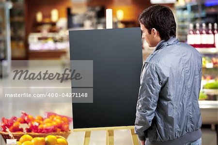 The young man looks at an empty board in shop