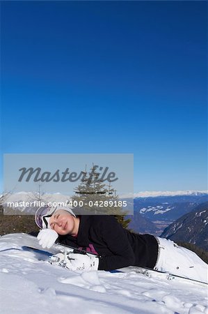 Female snowboarder is sleeping on snowboard