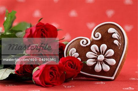 Gingerbread heart and red roses on red background. Shallow dof