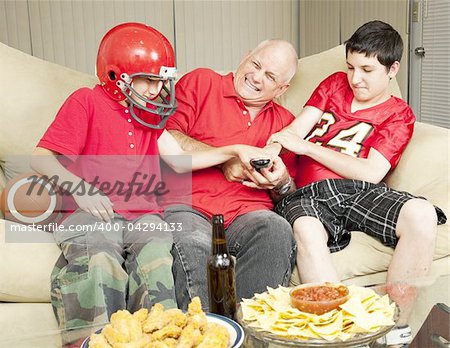 American football fans- father and sons - fighting for the television remote control.