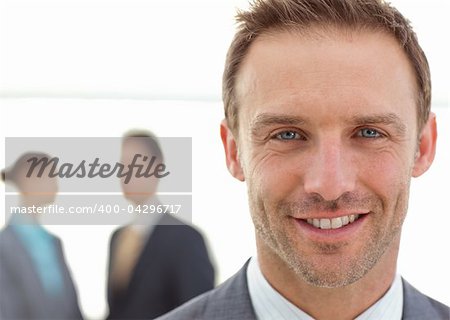 Cheerful businessman posing in front of his team while working on the background