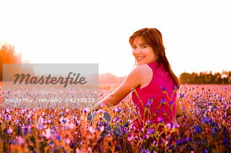 Beautiful young woman sitting on a flowery meadow