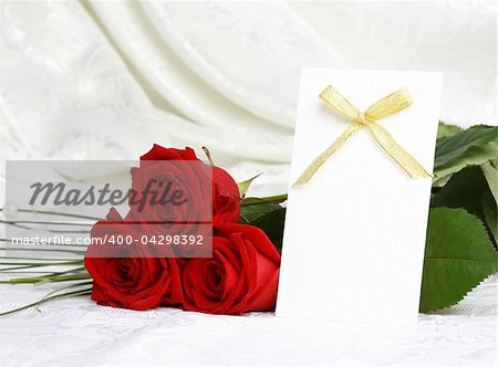 Beautiful red roses and invitation card on lace background