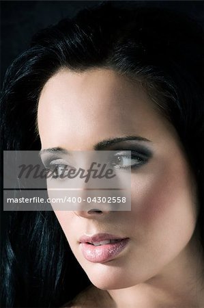 close up beauty portrait of young pretty brunette against a dark background