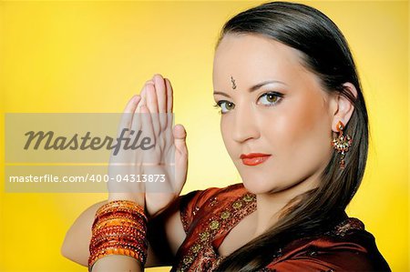 Young beautiful woman in indian traditional jewellery, bindi and make-up. yellow background
