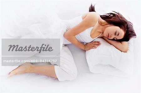 Stock image of young woman sleeping on white bed