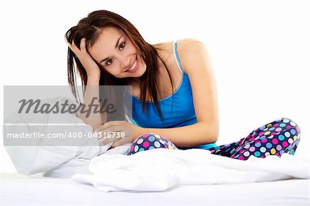 Stock image of young woman in pajamas sitting on bed over white background
