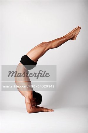 Young male dancer posing over grey background.