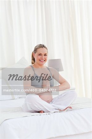 Pregnant woman practicing yoga on her bed