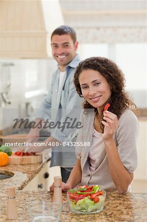Woman eating while her husband is cooking at home