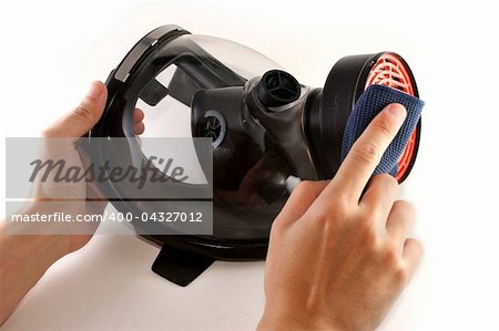 Hands cleaning a black gas mask with a piece of blue cloth