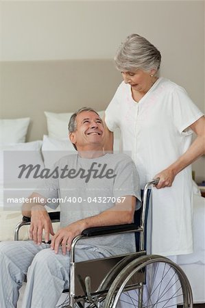 Retired man in his wheelchair with his wife
