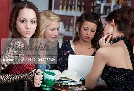 Cute looking young girl with her friends in a cafe discussing a project