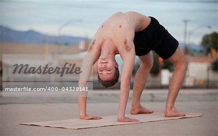 Fit young man in Urdhva Dhanurasana yoga posture