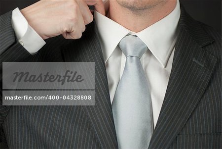 A close-up of a businessman adjusting his collar.