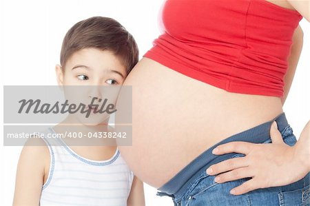 Surprised boy listening pregnant mother's belly over white background