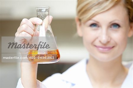 Close-up of a female scientist holding an erlenmeyer and smiling at the camera in her lab