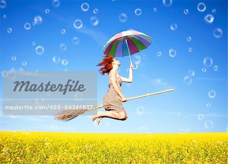 Red-haired girl fly with umbrella over rape field and bubbles around.