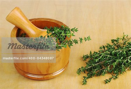 Fresh thyme with wooden mortar and pestle on wooden board (Selective Focus)