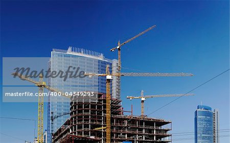 Construction site with tall cranes on background of modern office buildings