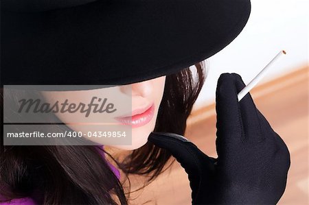 Portrait of a beautiful brunette  young woman with black hat, gloves and cigar
