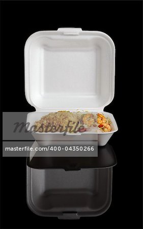 Chinese take-away food: Fried rice with king prawns and vegetables in a styrofoam box photographed on black