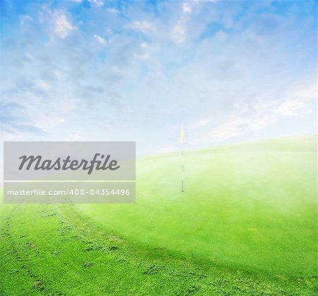 landscape of a green golf field with clouds and morning fog.  Shallow focus.