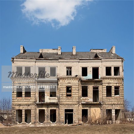 Abandoned damaged old house against blue cloudy sky