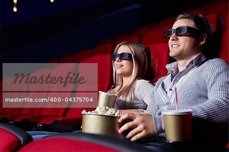 Attractive young couple in 3D glasses watching movies in cinema