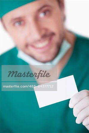 A young surgeon with a blank business card on a white background