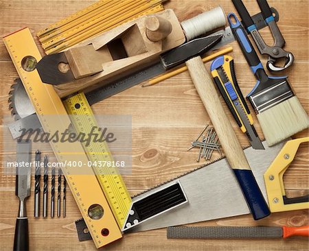 Working tools on a wooden boards background. Including saw, ruler, drill, nails, pliers,hammer, brush,thread,chisel and other.