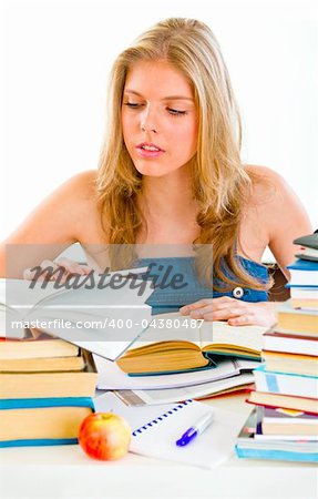 Concentrated teengirl sitting at table and searching in books